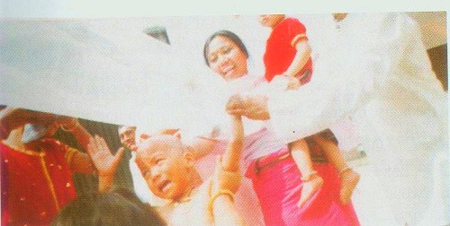 Kumaris pouring the water over the child during a Na-hutpa ceremony